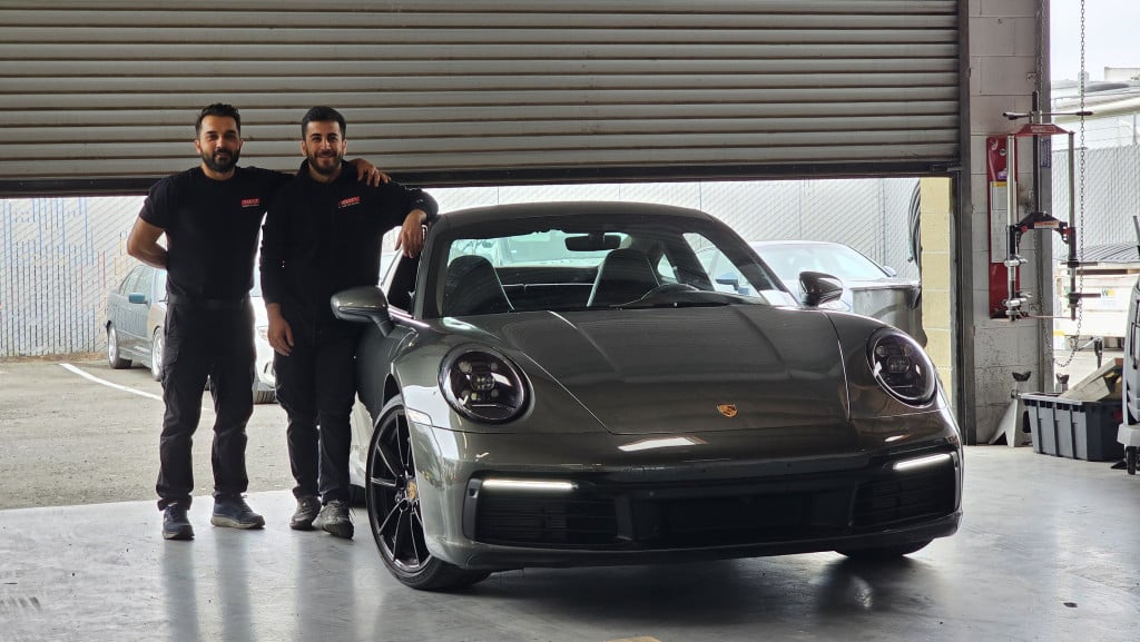 Select German Car Service team members with a Porsche 911 ready for pickup